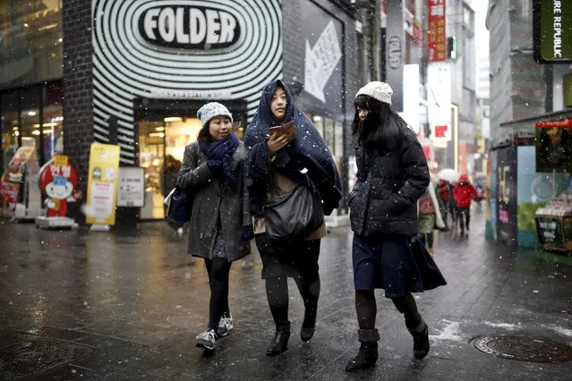 Tourists walk in the Myeongdong shopping district during snowfall in Seoul, South Korea, February 16, 2016. (Photo by Kim Hong-Ji/Reuters)