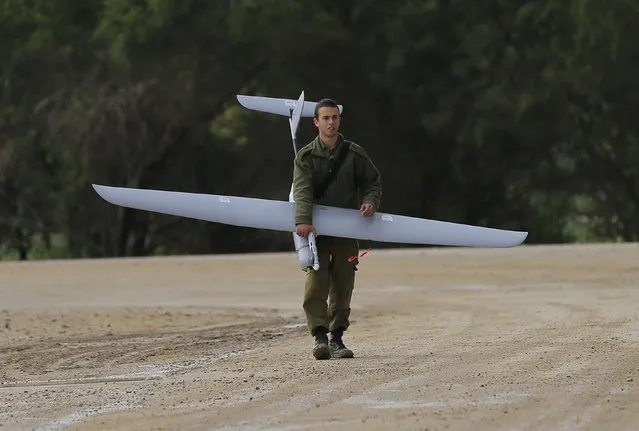 An Israeli soldier carries a drone near the Israel and Gaza border on Thursday, March 13, 2014. Gaza militants resumed rocket fire toward Israel on Thursday, striking the outskirts of two major cities a day after launching the largest barrage since an eight-day Israeli offensive in late 2012. Israel has responded with a series of airstrikes on militant targets. (Photo by Tsafrir Abayov/AP Photo)