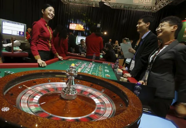 Kathryn Lagrata (L), 25, from Solaire Resort and Casino in Manila, Philippines, chats with judges as she takes part in an “All Asia Dealers Championship” at the Global Gaming Expo (G2E) Asia in Macau, China May 19, 2015. (Photo by Bobby Yip/Reuters)