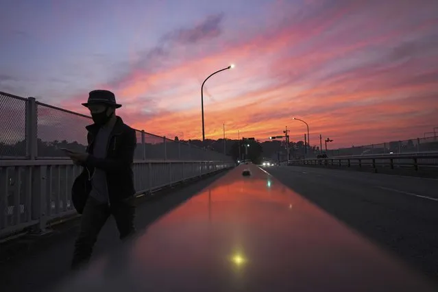 A man walks along a pedestrian bridge at sunset Friday, November 19, 2021, in Yokohama, near Tokyo. (Photo by Eugene Hoshiko/AP Photo)