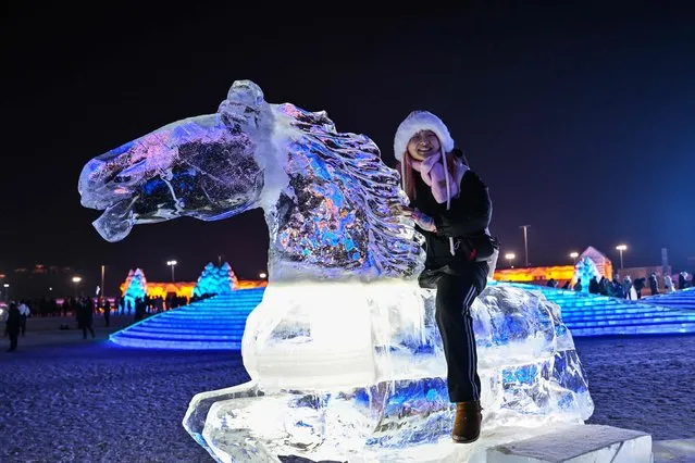 A woman poses while sitting on an ice horse at the Harbin Ice and Snow World in Harbin, in China's northeastern Heilongjiang province on January 5, 2023, during the opening ceremony of the 39th Harbin China International Ice and Snow Festival. (Photo by Hector Retamal/AFP Photo)