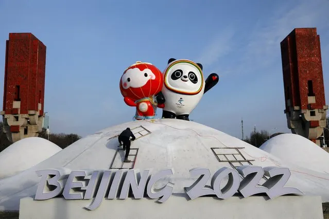 A worker sets up an installation featuring Bing Dwen Dwen, the Beijing 2022 Winter Olympic Mascot and Shuey Rhon Rhon, the 2022 Beijing Winter Paralympic Games Mascot, in Beijing, China on January 11, 2022. (Photo by Tingshu Wang/Reuters)
