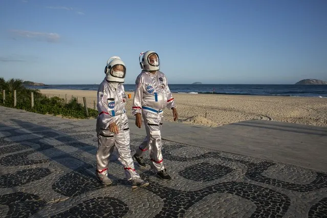 Accountant Tercio Galdino and wife Alicea walk in astronaut costumes as a way to protect themselves from COVID-19 and draw awareness to protective measures along Ipanema beach in Rio de Janeiro, Brazil, Saturday, March 20, 2021. The pair first began to traverse the iconic beaches fully suited in mid 2020 at the height of the first wave of the pandemic in Brazil, and now as cases surge once again they are taking their “astronaut walks” back to the promenades. (Photo by Bruna Prado/AP Photo)