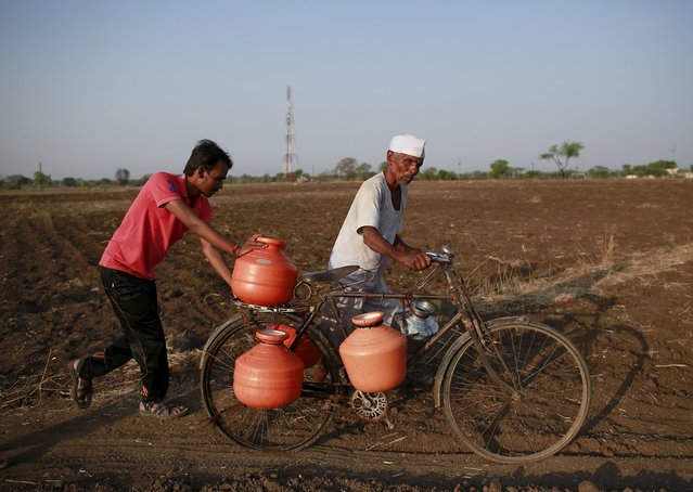 Residents push a bicycle loaded with water containers through a field in Latur, India, April 17, 2016. (Photo by Danish Siddiqui/Reuters)