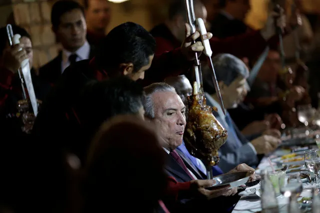 Brazil's President Michel Temer eats barbecue in a steak house after a meeting with ambassadors of meat importing countries of Brazil, in Brasilia, Brazil March 19, 2017. (Photo by Ueslei Marcelino/Reuters)