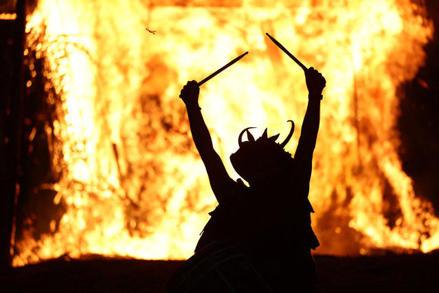A drummer performs as the Wicker Man goes up in flames during the Celtic fire festival Beltain in Waterlooville, southern England on May 4, 2024. The festival, a modern annual participatory arts event, celebrates the Gaelic May Day festival and marks the beginning of summer. Historically it was widely observed in Ireland, Scotland and the Isle of Man. Rituals were performed to protect cattle, people and crops, and to encourage growth. Special bonfires were kindled, whose flames, smoke and ashes were deemed to have protective powers. The people and their cattle would walk around or between bonfires, and sometimes leap over the flames or embers. All household fires would be doused and then re-lit from the Beltane bonfire. (Photo by Henry Nicholls/AFP Photo)