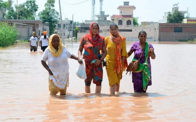 Indian villagers walk through flood waters following flooding waters in Kang Khurd, some 40 Km from Kapurthala on August 20, 2019. (Photo by Narinder Nanu/AFP Photo)