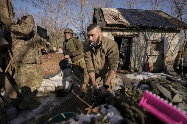 A Ukrainian serviceman washes a t-shirt at a frontline position, outside Popasna, Luhansk region, eastern Ukraine, Monday, February 14, 2022.. (Photo by Vadim Ghirda/AP Photo)