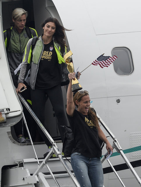 The U.S. women's national soccer team captain Christie Rampone, holding the trophy, and her teammates Hope Solo, center, and Abby Wambach, left, arrive at Los Angeles International Airport, Monday, July 6, 2015. The team defeated Japan 5-2 during Sunday's FIFA Women's World Cup in Vancouver. (Photo by Kevork Djansezian/Pool Photo via AP Photo)