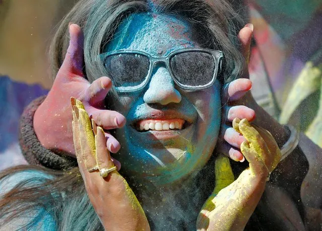 A woman reacts as coloured powder is put on her face during Holi celebrations in Ahmedabad, India, March 17, 2022. (Photo by Amit Dave/Reuters)