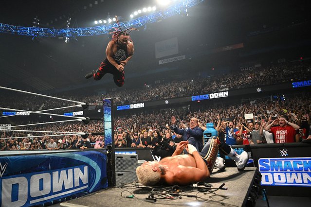 Jacob Fatu flies through the air as he goes off of the top rope towards WWE Undisputed Champion Cody Rhodes on the announcer table during WWE SmackDown at Allstate Arena on June 21, 2024 in Rosemont, Illinois.  (Photo by WWE/Getty Images)