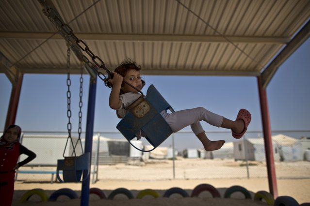 A Syrian girl plays on a swing while she and other children celebrate the first day of the Eid al-Fitr holiday that marks the end of the holy fasting month of Ramadan at Zaatari refugee camp, in Mafraq, Jordan, Friday, July 17, 2015. (Photo by Muhammed Muheisen/AP Photo)