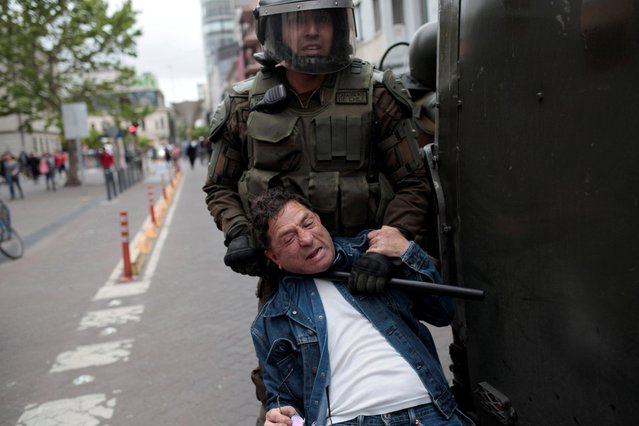 A demonstrator is detained by riot police by the neck with a baton during a protest against the government in Concepcion, Chile, October 19, 2019. (Photo by Juan Gonzalez/Reuters)