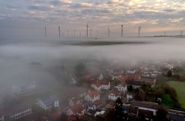 Fog floats over the village of Stetten, some 20 kilometres north of Kaiserslautern, Germany, Tuesday, March 19, 2024, with a wind energy plant in the background. (Photo by Michael Probst/AP Photo)