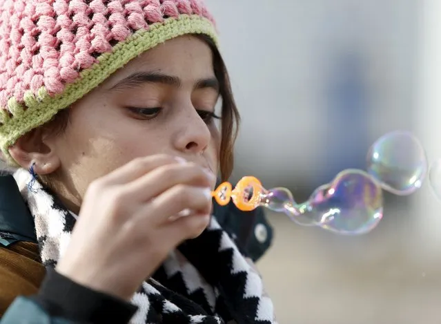 A child migrant blows soap bubbles as refugees and migrants wait to continue their journey towards western Europe from the Macedonia-Serbia border at a transit camp in the village of Presevo, Serbia, February 2, 2016. (Photo by Darrin Zammit Lupi/Reuters)