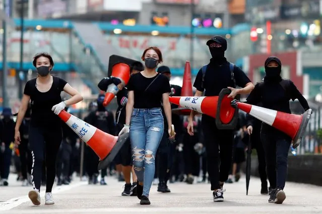 Protesters walk down the road with traffic cones to build a barricade in Causeway Bay, Hong Kong, China on November 11, 2019. (Photo by Thomas Peter/Reuters)