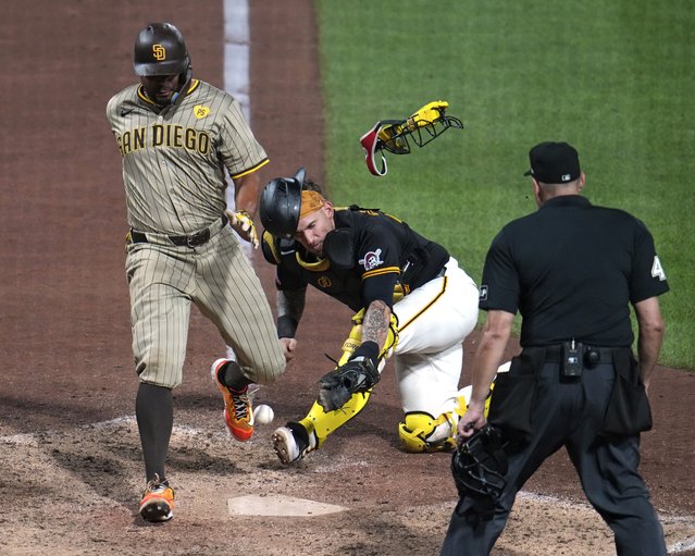 San Diego Padres' Xander Bogaerts, left, knocks the ball out of the glove of Pittsburgh Pirates catcher Yasmani Grandal, center, to score from third on a sacrifice fly by Jackson Merrill off relief pitcher Colin Holderman during the tenth inning of a baseball game in Pittsburgh, Wednesday, August 7, 2024. (Photo by Gene J. Puskar/AP Photo)