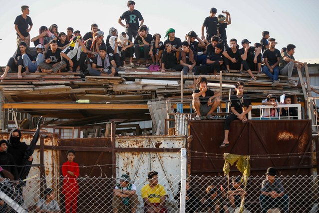 People watch as Shiite Muslims re-enact the Battle of Karbala as they mark the peak of Ashura, a 10-day period commemorating the seventh century killing of Prophet Mohammed's grandson Imam Hussein, in Sadr City in eastern Baghdad, on July 17, 2024. (Photo by Ahmad Al-Rubaye/AFP Photo)