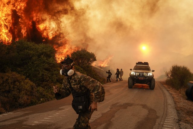 Firefighters and volunteers work to extinguish a wildfire in Krieza, on Evia Island, Greece, on Tuesday, July 30, 2024. A strong wind in the Aegean Sea is increasing wildfire risks, while parts of the mainland will see heat of 43C by the end of the week. (Photo by Nick Paleologos/Bloomberg)