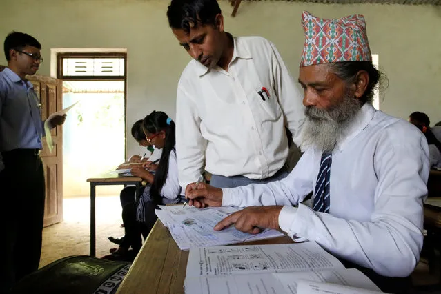 A teacher helps Durga Kami, 68, who is studying in the tenth grade at Shree Kala Bhairab Higher Secondary School, to fill his registration form to apply for the upcoming School Leavers Certificate Exams in Syangja, Nepal, June 6, 2016. (Photo by Navesh Chitrakar/Reuters)