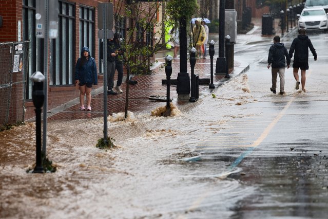 People walk next to fast-flowing flood waters running down the town’s main King Street as Tropical Storm Helene strikes, in Boone, North Carolina on September 27, 2024. (Photo by Jonathan Drake/Reuters)