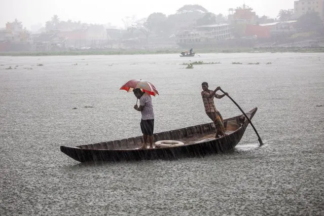 People cross the Buriganga river as they shelter themselves under umbrellas during the rain and rough condition caused by cyclone Asani in Dhaka, Bangladesh, 10 May 2022. According to the Bangladesh Meteorological Department (MET) office report, severe cyclone Asani is likely to weaken gradually into a cyclonic storm in next 12 hours and move northwest direction of the Bay of Bengal and the storm is expected without making a landfall. (Photo by Monirul Alam/EPA/EFE)