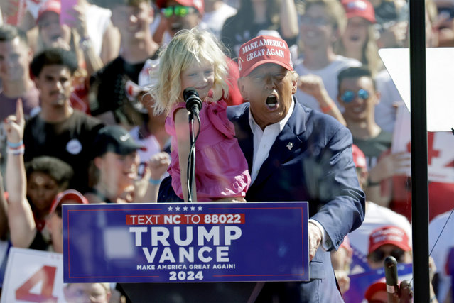 Republican presidential nominee former President Donald Trump holds his granddaughter Carolina Trump as he speaks at a campaign event at Wilmington International Airport in Wilmington, N.C., Saturday, September 21, 2024. (Photo by Chris Seward/AP Photo)