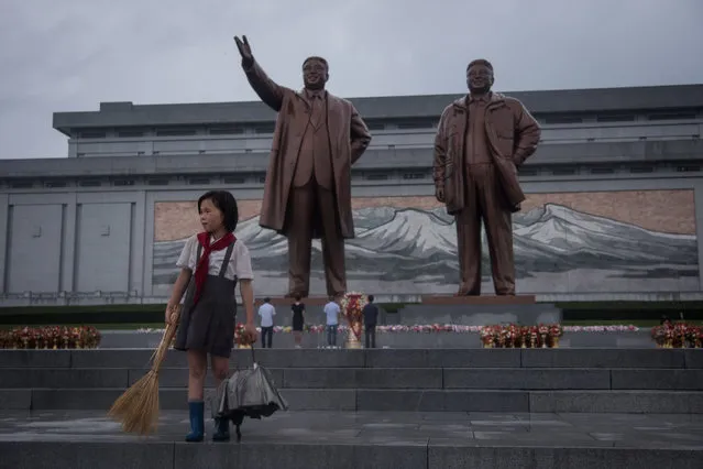 A young girl cleans steps as people bow before the statues of late North Korean leaders Kim Il- Sung (L) and Kim Jong- Il (R) as the country marks “Victory Day” at Mansu hill in Pyongyang on July 27, 2017 July 27, which is the 64 th anniversary of the signing of the Korean Armistice Agreement, is a public holiday in the nuclear- armed North and celebrated as Victory Day. (Photo by Ed Jones/AFP Photo)