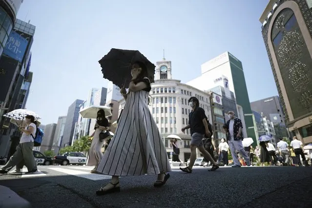 People walk over a pedestrian crossing under an intense sun Tuesday, June 28, 2022, in Tokyo. (Photo by Eugene Hoshiko/AP Photo)