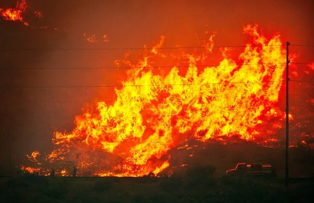 Firefighters, lower left, are visible as fire races up the east side of Numeral Mountain from Highway 97A, close to Entiat, Wash., Wednesday night, July 9, 2014. (Photo by Don Seabrook/AP Photo/The Wenatchee World)