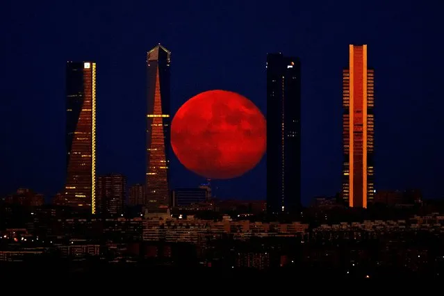 The moon rises in the sky as seen through the Four Towers or C.T.B.A. (Cuatro Torres Business Area), one of the main symbols of Madrid, Spain, Monday, August 11, 2014. (Photo by Daniel Ochoa de Olza/AP Photo)