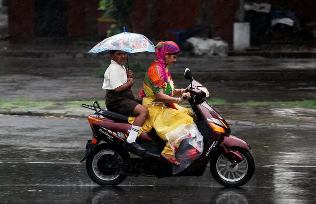 A boy holds an umbrella as he travels on a scooter with his mother during rains in Chandigarh, India, July 14, 2016. (Photo by Ajay Verma/Reuters)