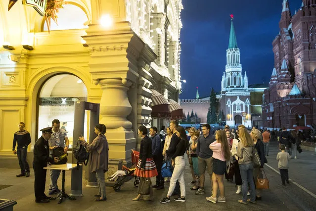 People are checked by security guards before entering GUM, State Shop, at Red square in Moscow, Russia, Wednesday, September 13, 2017. Heavy security was in place in central Moscow outside the flagship department store GUM following a bomb threat. GUM was one of dozens of major buildings, including shopping centers, railways stations, hotels and universities, in the Russian capital targeted on Wednesday by anonymous telephone hoaxers. (Photo by Pavel Golovkin/AP Photo)