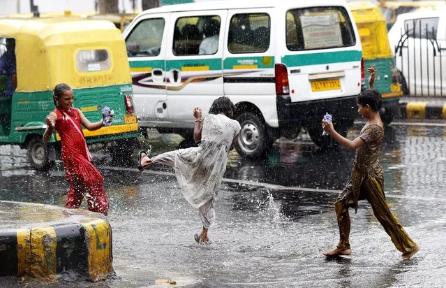 A picture made available on 08 July shows Indian children playing in a pool of water on a road during monsoon showers in New Delhi, India, 07 July 2016. The summer monsoon season in India usually begins in the months of June and July and lasts until October. (Photo by Rajat Gupta/EPA)
