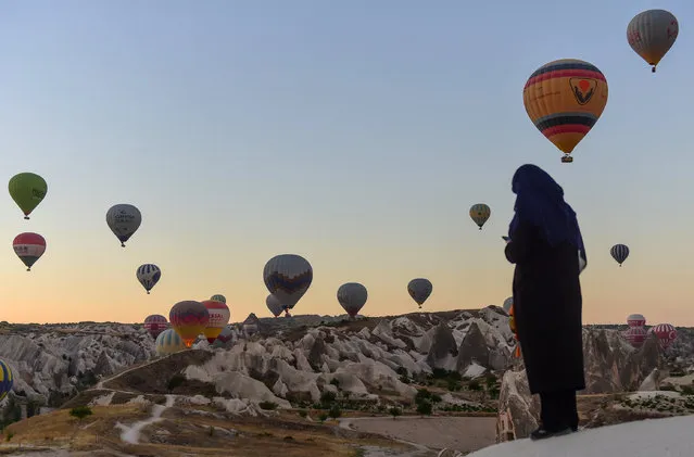 Hot air balloons glide during a flight over Nevsehir in Turkey's historical Cappadocia region, Central Anatolia, eastern Turkey, on September 5, 2017. The rides by hot air balloon start in the morning as the balloons cannot fly at temperatures over 28 degrees Celsius and during extreme windy conditions. Cappadocia is one of the most famous tourist sites in Turkey and has been listed as a World Heritage Site in 1985. (Photo by Yasin Akgul/AFP Photo)