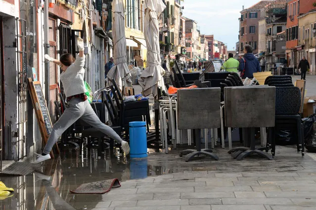 A woman jumps over a puddle during cleaning following a flooding in Venice, Italy, Thursday, November 14, 2019. The worst flooding in Venice in more than 50 years has prompted calls to better protect the historic city from rising sea levels as officials calculated hundreds of millions of euros in damage. The water reached 1.87 meters above sea level Tuesday, the second-highest level ever recorded in the city. (Photo by Andrea Merola/ANSA via AP Photo)