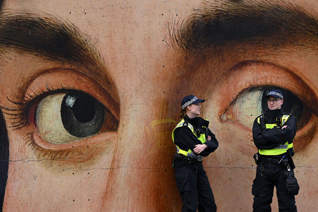 Police officers chat in front of a reproduction of “Portrait of a Man” by Italian painter Antonello da Messina ahead of the 'London Rally For Palestine' in Trafalgar Square, central London on November 4, 2023, calling for a ceasefire in the conflict between Israel and Hamas. Thousands of civilians, both Palestinians and Israelis, have died since October 7, 2023, after Palestinian Hamas militants based in the Gaza Strip entered southern Israel in an unprecedented attack triggering a war declared by Israel on Hamas with retaliatory bombings on Gaza. (Photo by Justin Tallis/AFP Photo)