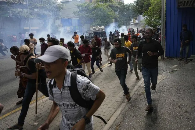 Anti-government protesters run as police fire tear gas and chase them during a protest march in Colombo, Sri Lanka, Thursday, August 18, 2022. (Photo by Eranga Jayawardena/AP Photo)