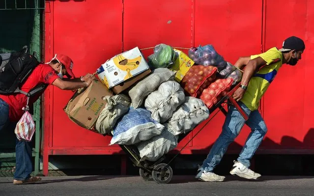 Two men carry a cart loaded with fresh goods at a street in Tegucigalpa on June 8, 2020, after the governmet announced the resumption of economic activity, amid the COVID-19 pandemic. Honduras reopens its business activities, cautiously, after almost three months of confinement, though, according to experts, at the worst time to do so due to the rapid rise of the coronavirus and at high risk of closing again. (Photo by Orlando Sierra/AFP Photo)