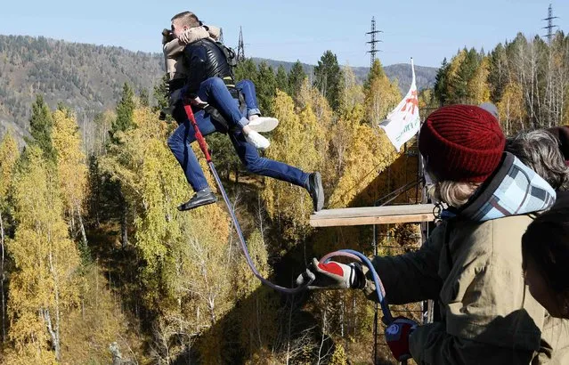 Members of the “Flying Freak” amateur rope-jumping group jump from a 44-metre high (144-feet high) waterpipe bridge in the Siberian Taiga area outside Krasnoyarsk, September 28, 2014. (Photo by Ilya Naymushin/Reuters)