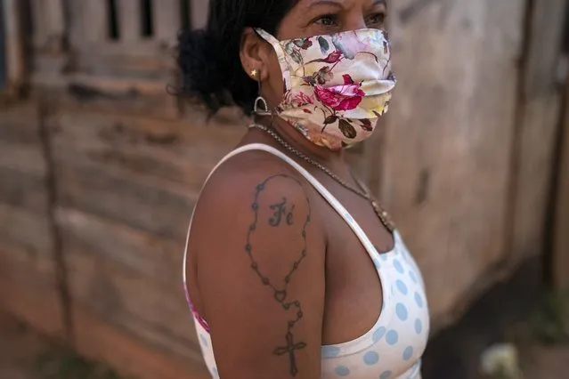 Resident Luciana Ferreira da Cruz poses for the photo featuring a rosary tattoo on her arm coupled with the Portuguese word for faith, in an area occupied by squatters in a poor region amid the outbreak of the new coronavirus in Rio de Janeiro, Brazil, Friday, June 26, 2020. “Everything has a start and an end. We gonna win this pandemic”, says the 47-year-old woman who works collects aluminum cans to cash in for money. (Photo by Leo Correa/AP Photo)