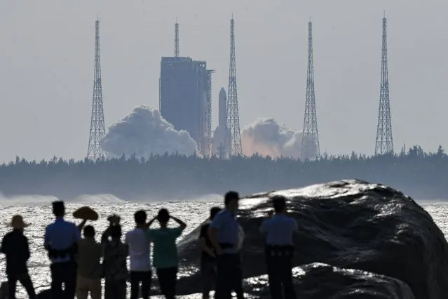 In this photo released by Xinhua News Agency, people watch the Long March-5B Y4 carrier rocket carrying the space lab module Mengtian, blasts off from the Wenchang Satellite Launch Center in south China's Hainan Province, Monday, October 31, 2022. China has launched the third and final module to complete its permanent space station, realizing a more than decade-long endeavor to maintain a constant crewed presence in orbit. (Photo by Yang Guanyu/Xinhua via AP Photo)