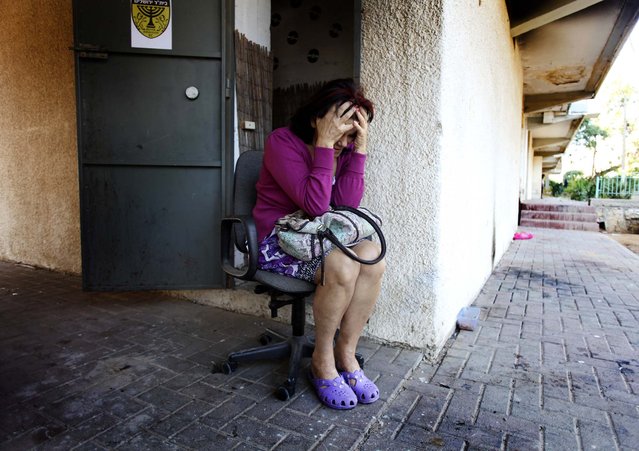 A woman sits outside a shelter near an apartment building that was struck by a rocket fired from Gaza, in Kiryat Malachi. (Photo by Rina Castelnuovo/The New York Times)