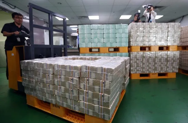 An employee moves cash bundles at the Bank of Korea (BOK) in Seoul, South Korea, 22 September 2015, as the central bank releases a large amount of cash to commercial banks ahead of the Korean harvest festival of Chuseok, during which cash demand is usually high. This year the traditional holiday falls on 27 September. (Photo by EPA/Yonhap)