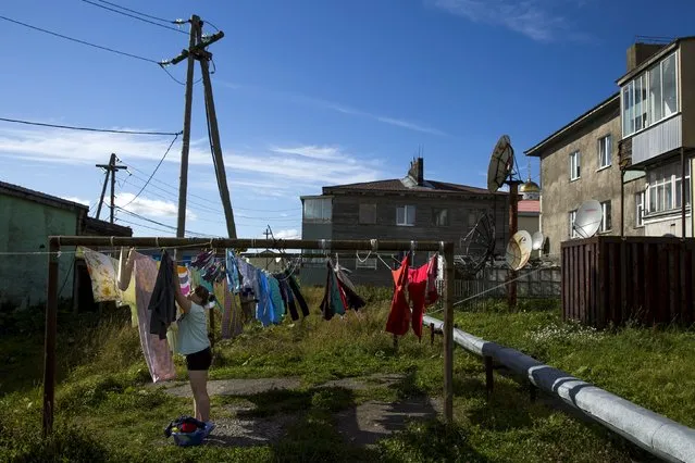 A woman hangs up laundry in the centre of Yuzhno-Kurilsk, the main settlement on the Southern Kurile island of Kunashir September 14, 2015. (Photo by Thomas Peter/Reuters)