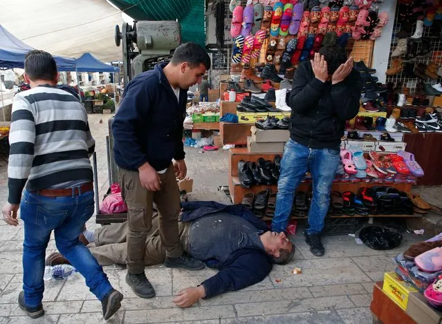 A Palestinian man lies on the ground after being wounded during clashes with Israeli security forces in the city centre of the West Bank town of Hebron on December 10, 2017. New protests flared in the Middle East and elsewhere over US President Donald Trump's declaration of Jerusalem as Israel's capital, a move that has drawn global condemnation and sparked days of unrest in the Palestinian territories. (Photo by Hazem Bader/AFP Photo)
