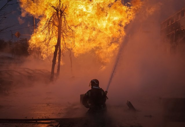 A firefighter works at the site of a fire after a Russian missile strike in Kyiv, Ukraine on January 2, 2024. (Photo by Yevhen Kotenko/Reuters)