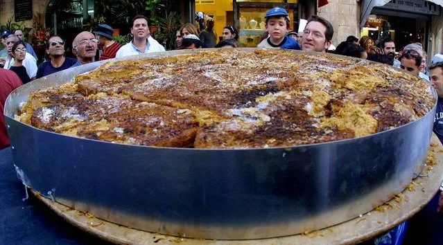 Residents of Jerusalem peek over the top of a giant Kugel, a traditional Jewish sweet dish, which was named world's largest by the Guinness Book of World Records August 1, 2002. (Photo by ZOOM 77/Associated Press)