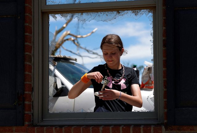 Mia Wells holds a small trophy found in the garage while she and her family dig through the damage done to their home after one of a series of tornadoes hit Morganfield, Kentucky, on May 17, 2025. (Photo by Lylee Gibbs/Reuters)
