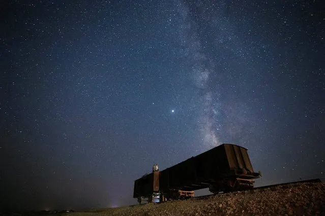 People sit atop an old train carriage at night as they watch the annual Perseid meteor shower near the Israel-Egypt border in Ezuz, southern Israel on August 12, 2020. (Photo by Amir Cohen/Reuters)